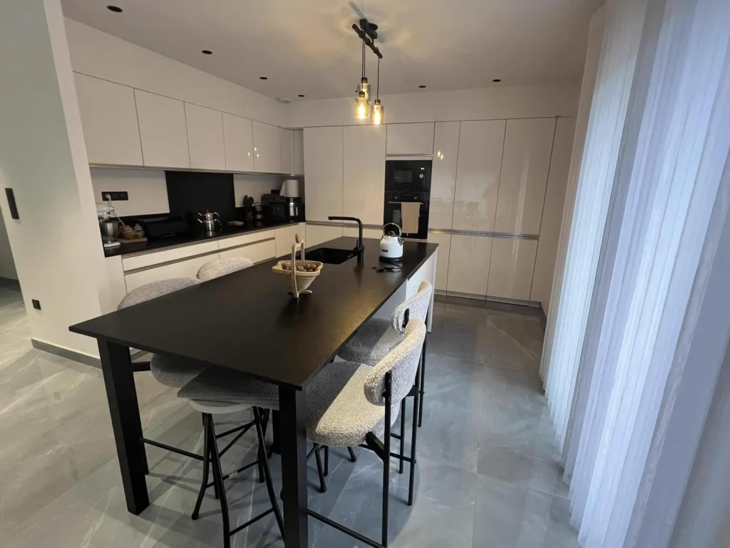 Cuisine blanche brillante avec plan de travail en granit noir à Valentigney